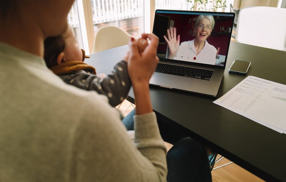 Long-distance caregiving 1 A woman and child sit at a table with a laptop, engaged in long distance caregiving for aging in place.