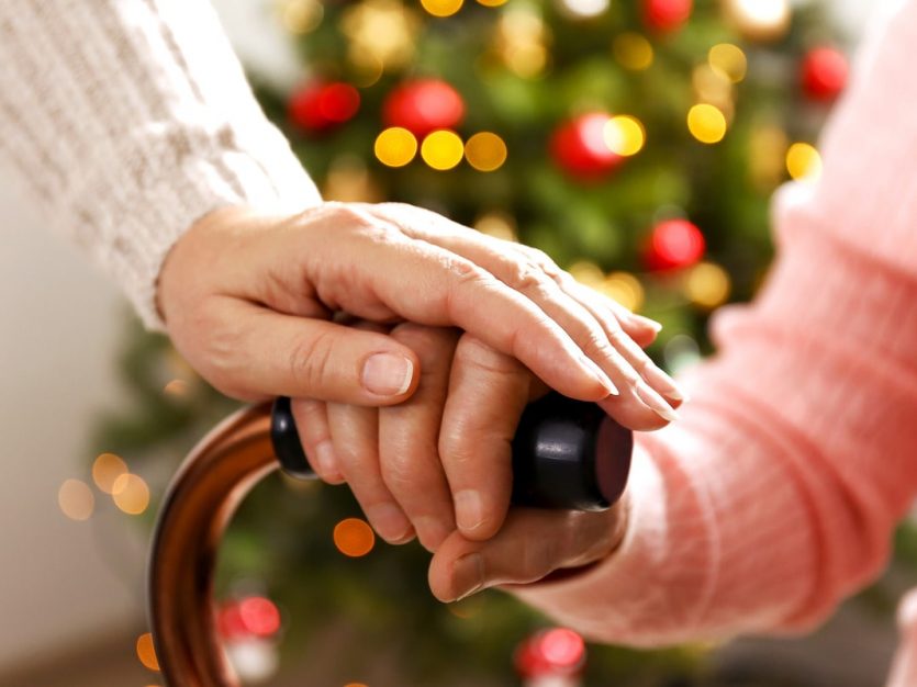 A caring woman supports an elderly person by holding their hand, showing compassion and companionship.