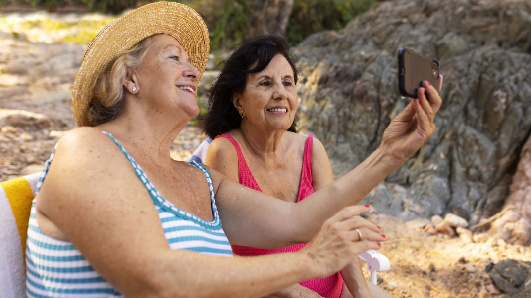 Two seniors clicking a selfie at the beach during summer vacation