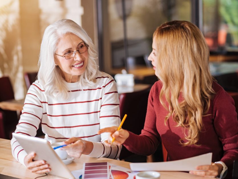 Older adult female and young adult female having a discussion at a cafe.
