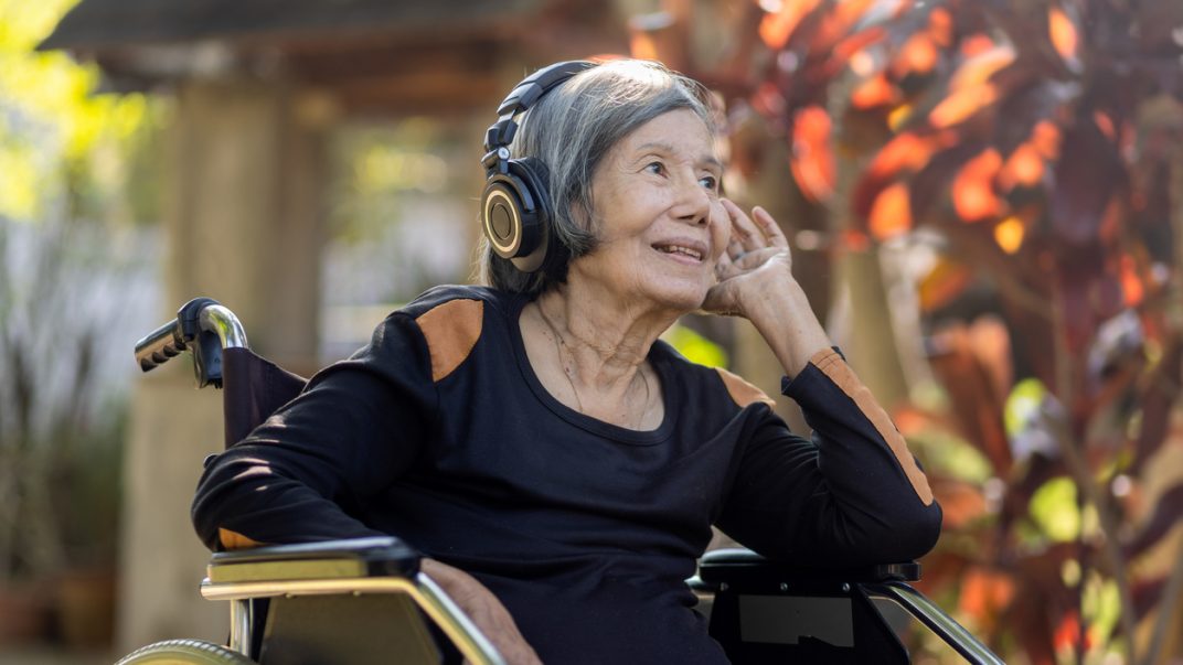 older woman in a wheel chair wearing headphones
