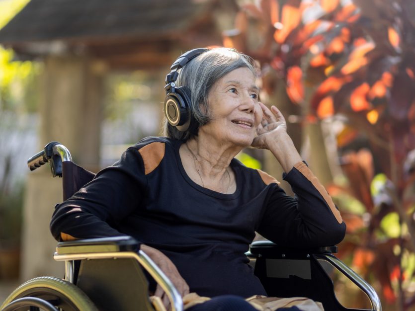 older woman in a wheel chair wearing headphones