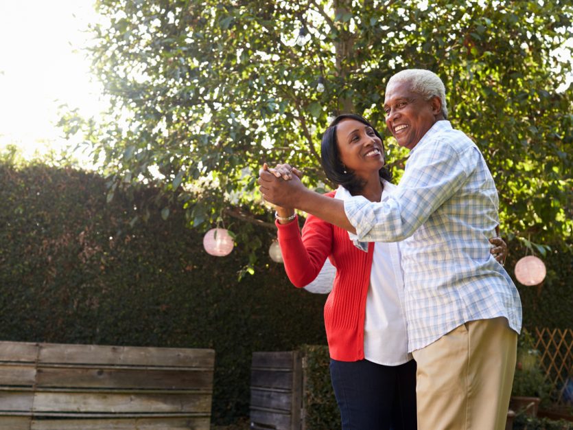 Older adult couple ballroom dancing in their backyard.
