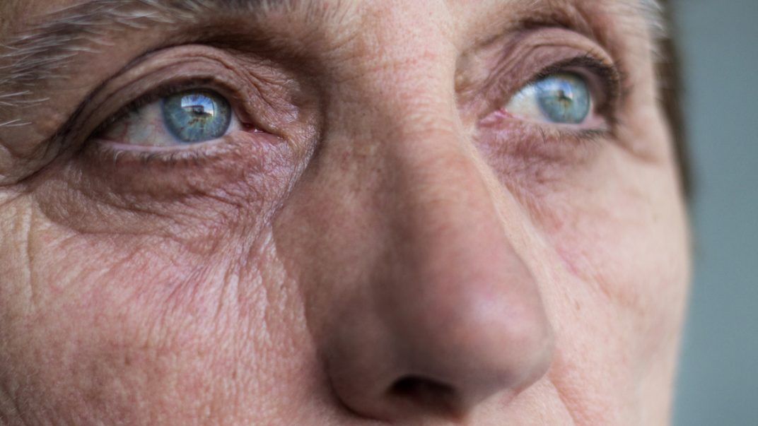 Close up of a senior woman's face and eyes looking off into the distance.
