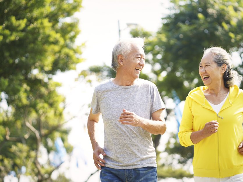 Male and female older adults running outdoors.