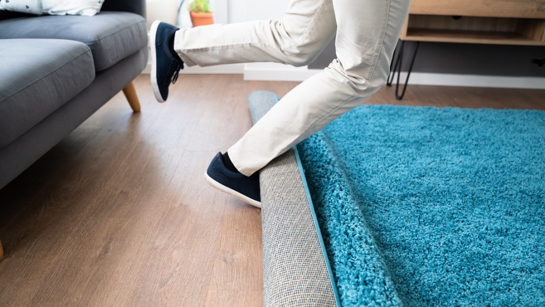 3 populations that benefit from falls prevention strategies 1 Legs tripping over a rug in a living room.