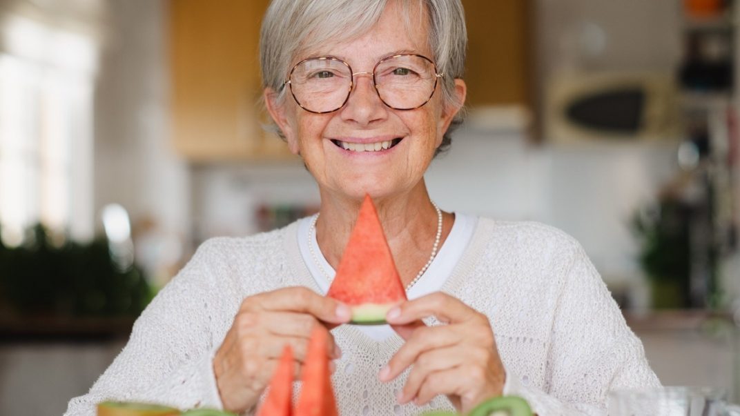 Diet and cardiovascular disease: What works? 1 Elderly woman sitting down and smiling with a slice of watermelon in her hands.
