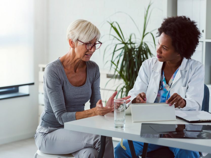 Female caregiver speaking with female doctor in a doctor’s office.