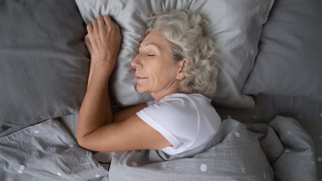 Older adult female sleeping in bed.