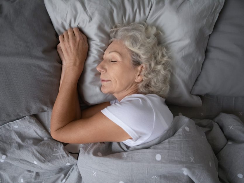 Older adult female sleeping in bed.