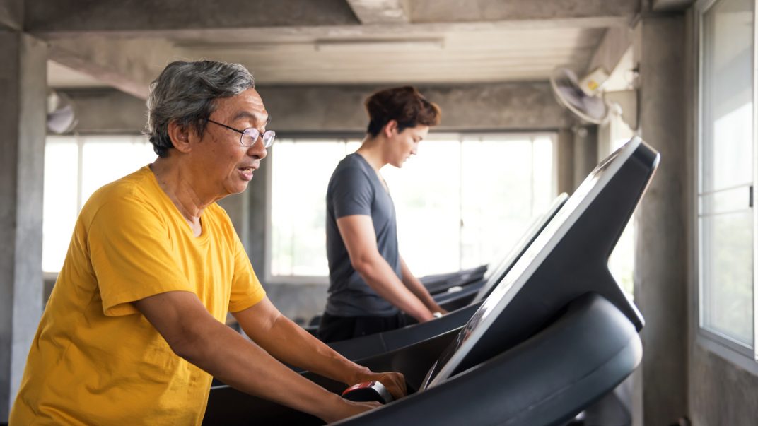 Older adult male walking on a treadmill.