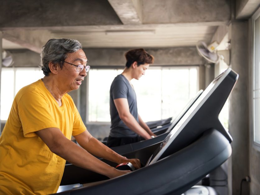 Older adult male walking on a treadmill.