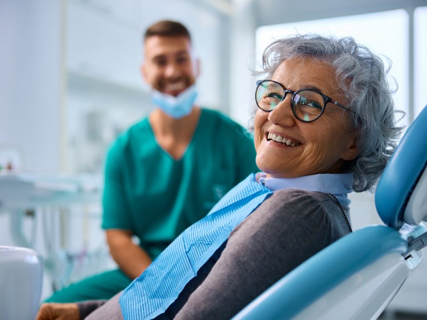 A woman sitting in a chair with a dentist behind her