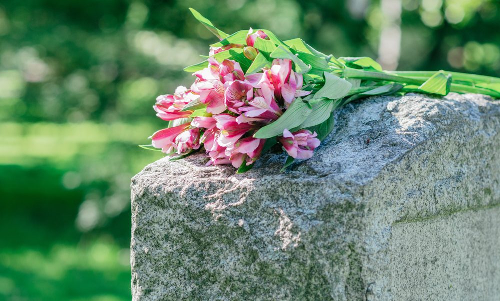 Headstone In Cemetery With Flowers For Concept Of Death