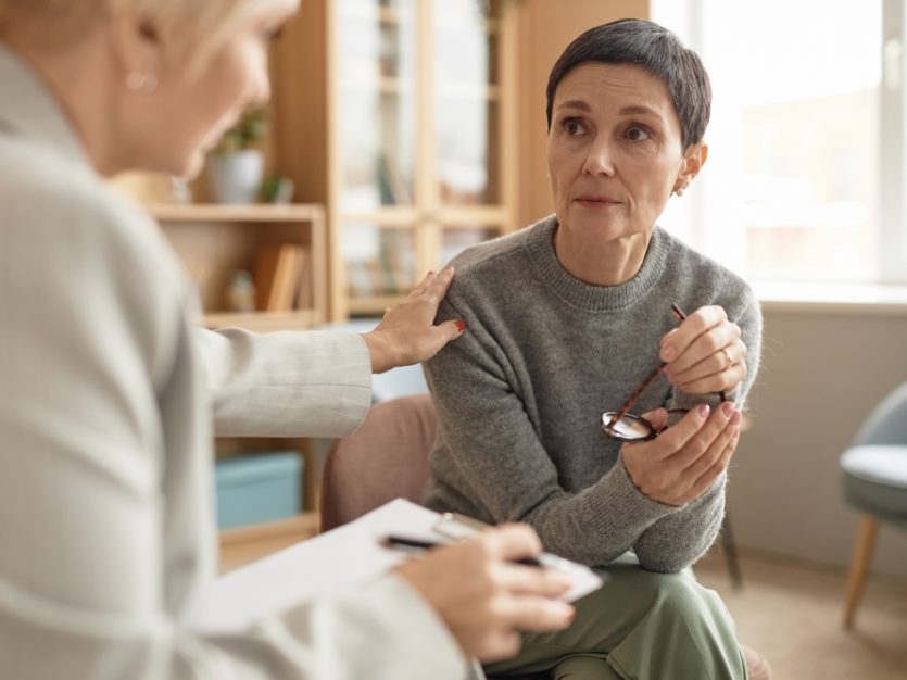 A woman holding glasses and looking at another woman