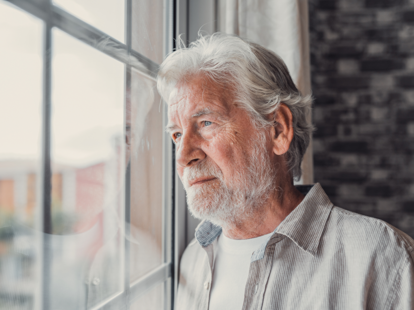 Elderly man gazing out window. - mental health and aging