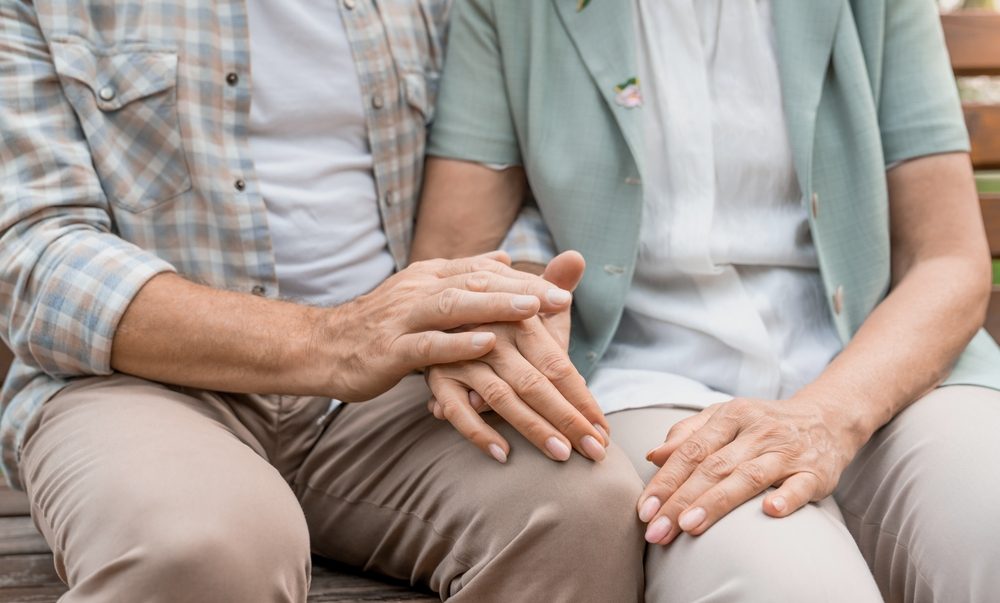 Senior couple holding hands on bench